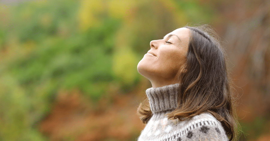 Hero image of a middle aged woman outside taking a deep breath